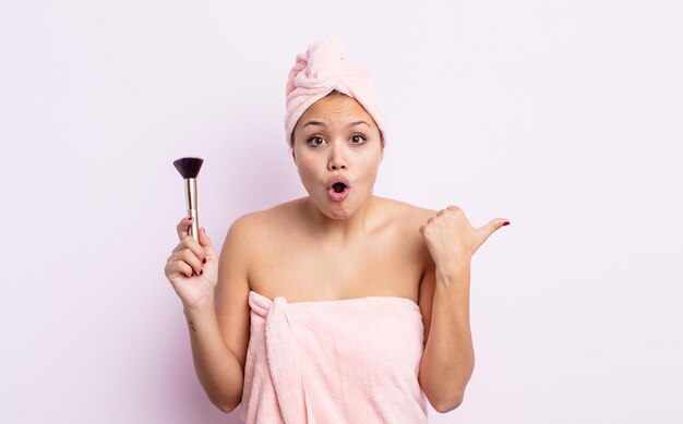 Spaanse mooie vrouw die verbaasd in ongeloof kijkt. make-up borstel concept