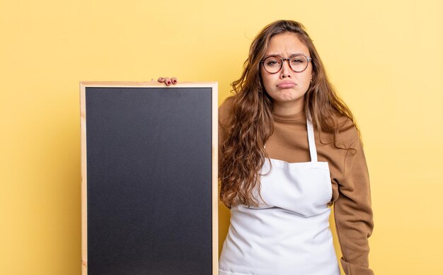 Spaanse mooie vrouw die verdrietig en zeurt met een ongelukkige blik en huilend schoolbordkopieerruimteconcept