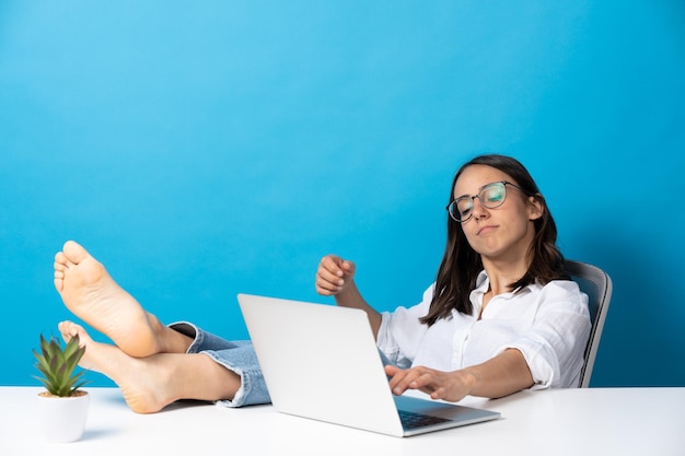 Spaanse mooie vrouw die voeten op bureau werkt