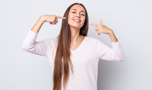 Spaanse mooie vrouw die vol vertrouwen glimlacht en wijst naar haar eigen brede glimlach, positieve, ontspannen, tevreden houding