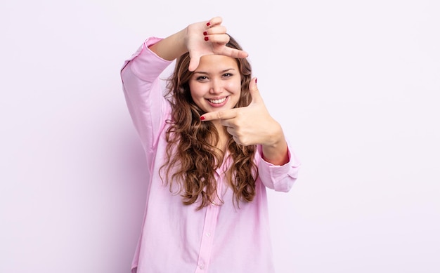 Spaanse mooie vrouw die zich gelukkig, vriendelijk en positief voelt, lacht en een portret of fotolijst maakt met handen