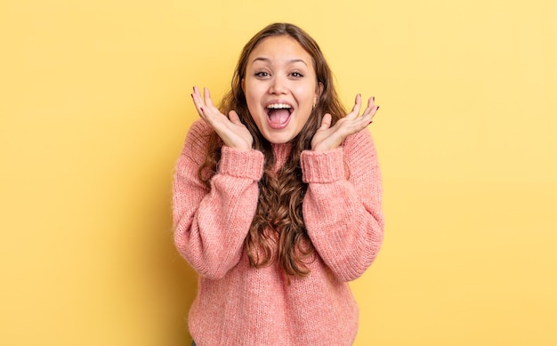 Foto spaanse mooie vrouw die zich geschokt en opgewonden voelt, lacht, verbaasd en blij vanwege een onverwachte verrassing