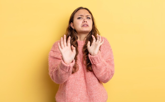 Spaanse mooie vrouw die zich verdoofd en bang voelt, bang voor iets angstaanjagends, met de handen vooraan open en zegt blijf weg