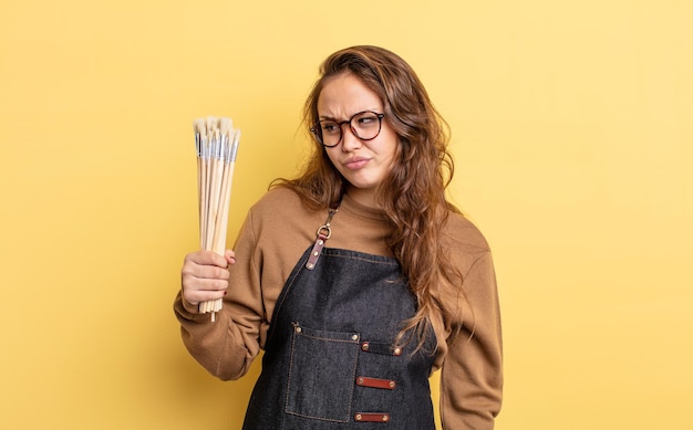 Spaanse mooie vrouw die zich verdrietig, overstuur of boos voelt en opzij kijkt. artiest met borstels concept