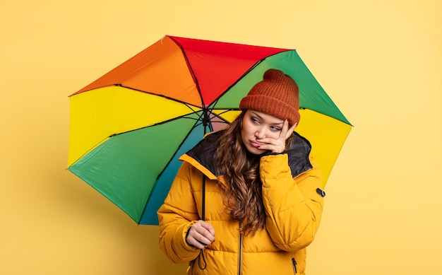 Spaanse mooie vrouw die zich verveeld, gefrustreerd en slaperig voelt na een vermoeiende paraplu concept