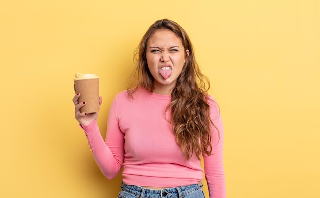 Spaanse mooie vrouw voelt zich weerzinwekkend en geïrriteerd en tong uit. afhaal koffie concept