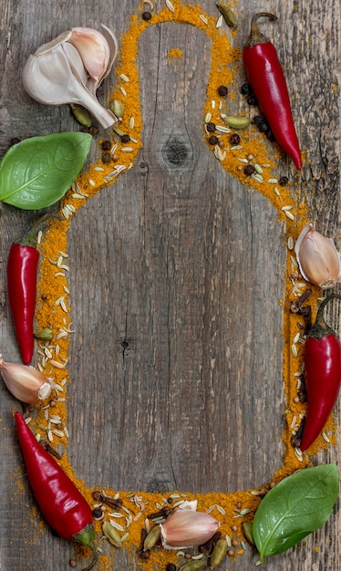 Foto spaanse peper, knoflook, basilicum, steranijs en kruiden op oude houten achtergrond