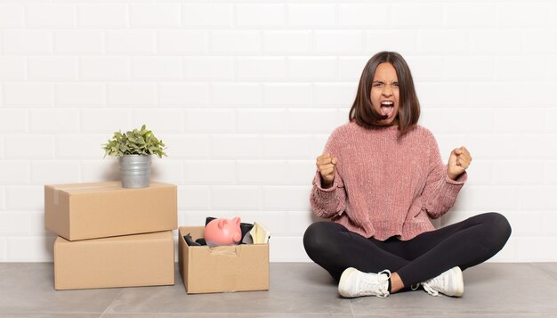 Spaanse vrouw die agressief schreeuwt met een boze uitdrukking of met gebalde vuisten om succes te vieren