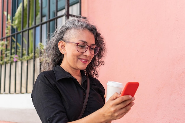 Spaanse vrouw die een bericht verzendt op een mobiele telefoon tijdens een wandeling in de stedelijke omgeving