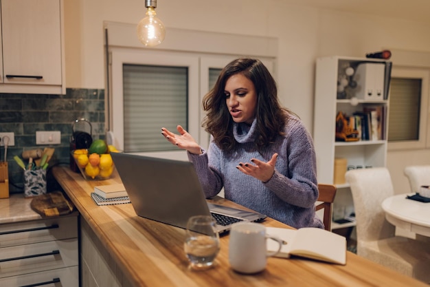 Spaanse vrouw die een laptop gebruikt terwijl ze vanuit huis werkt