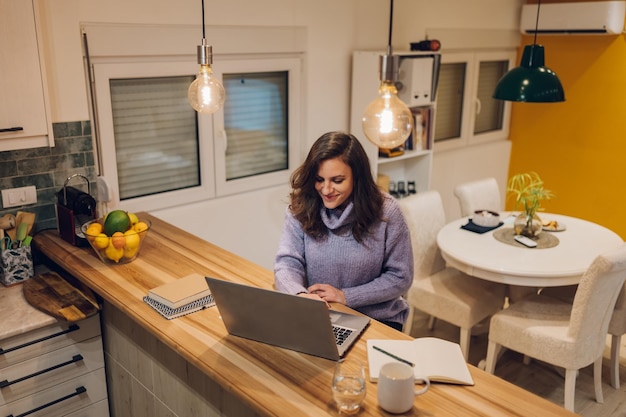 Spaanse vrouw die een laptop gebruikt terwijl ze vanuit huis werkt