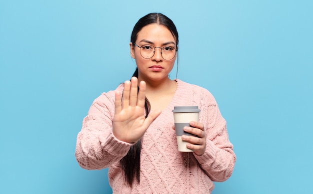 Spaanse vrouw die ernstig, streng, ontevreden en boos kijkt die open palm toont die stopgebaar maakt