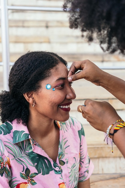 Spaanse vrouw die glitter aanbrengt op het gezicht van haar vriendin tijdens carnaval