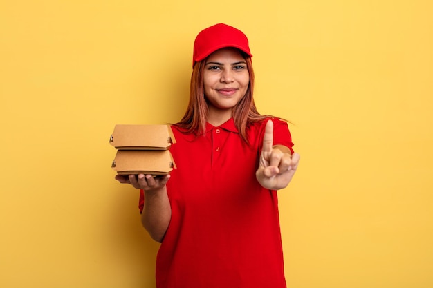 Spaanse vrouw die trots en vol vertrouwen glimlacht en nummer één maakt. afhaal levering concept