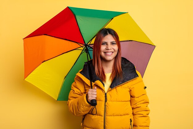 Spaanse vrouw die vrolijk lacht met een hand op de heup en zelfverzekerd regen- en parapluconcept