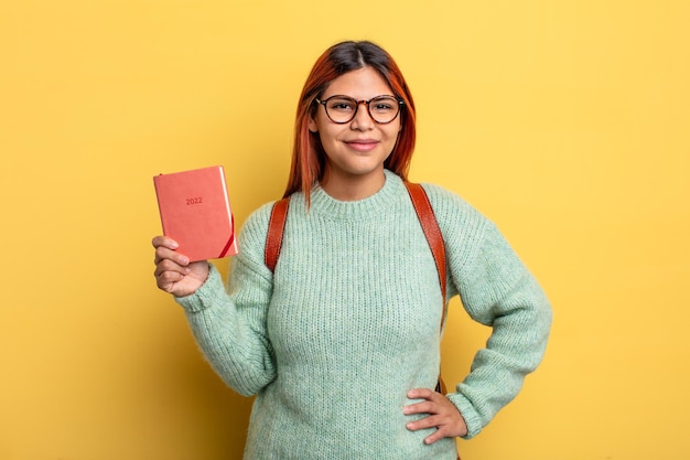 Spaanse vrouw die vrolijk lacht met een hand op de heup en zelfverzekerd. student en kalenderconcept