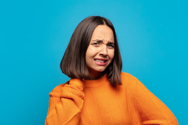 Spaanse vrouw die zich gestrest, gefrustreerd en moe voelt, pijnlijke nek wrijft, met een bezorgde, onrustige blik