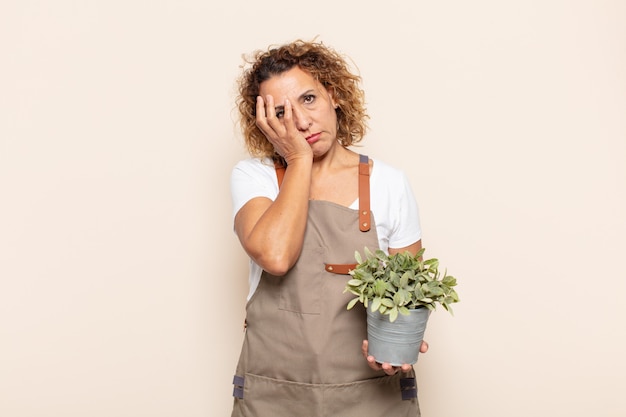 Spaanse vrouw van middelbare leeftijd die zich verveeld, gefrustreerd en slaperig voelt na een vermoeiende, saaie en vervelende taak, gezicht met de hand vasthoudend