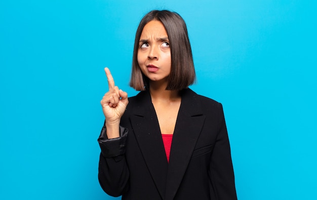 Spaanse vrouw voelt zich als een genie die trots haar vinger in de lucht houdt nadat ze een geweldig idee heeft gerealiseerd door eureka te zeggen