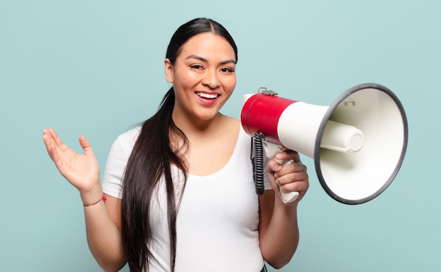 Spaanse vrouw voelt zich blij, verrast en opgewekt, lacht met een positieve houding, realiseert zich een oplossing of idee