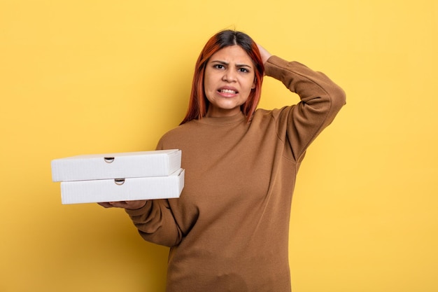 Spaanse vrouw voelt zich gestrest, angstig of bang met de handen op het hoofd om pizza's weg te halen