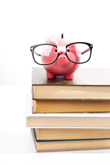 Spaarvarken op een stapel van boekconcept onderwijskosten