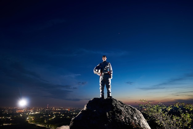 밤 하늘 아래 바위 산에 서 있는 우주 여행자