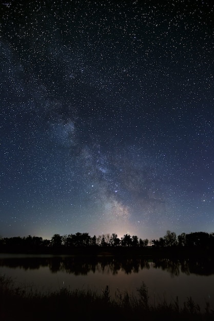 写真 夜空に星のある空間。川と木々のある風景を長時間露光で撮影します。