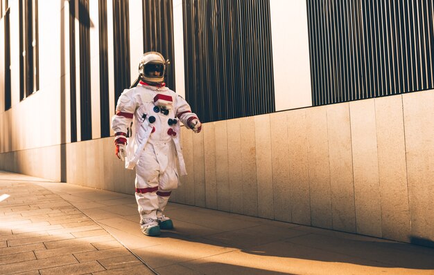 未来の駅にいる宇宙飛行士。都市部を歩く宇宙服を持つ男