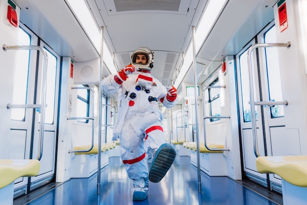 Spaceman in een futuristisch station. Man met ruimtepak vertrekt naar zijn werk en haalt de trein