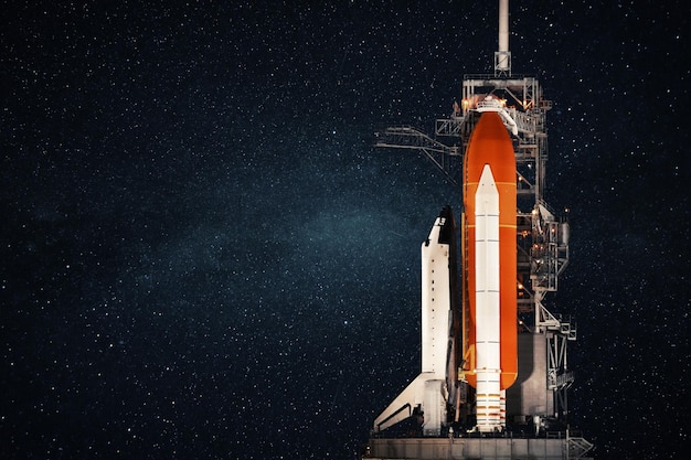 Spaceshuttle staat aan de basis en bereidt zich voor om te lanceren tegen de achtergrond van de sterrenhemel Ruimteraketconcept