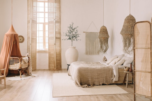 사진 흰색 벽과 따뜻한 보헤미안 톤의 대형 침대가 있는 넓고 밝은 침실 밀짚 샹들리에