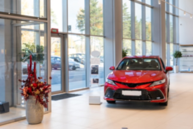 Foto concessionaria di auto spaziosa con una costosa foto di un'auto rossa con sfocatura