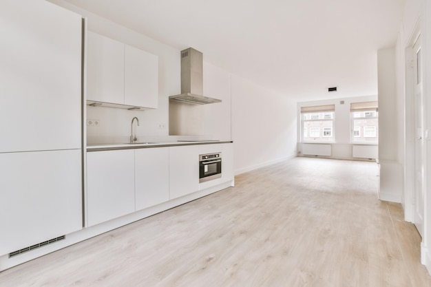 Spacious empty bright room with a corner kitchen in white in a modern house