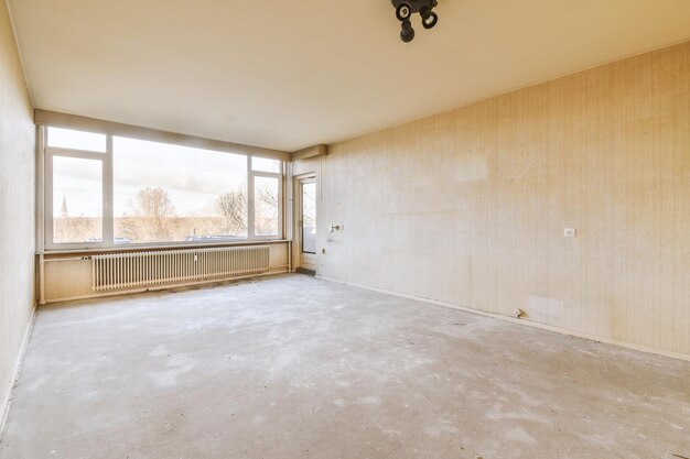 A spacious empty room with a large panoramic window with bare walls and floor in a cozy house