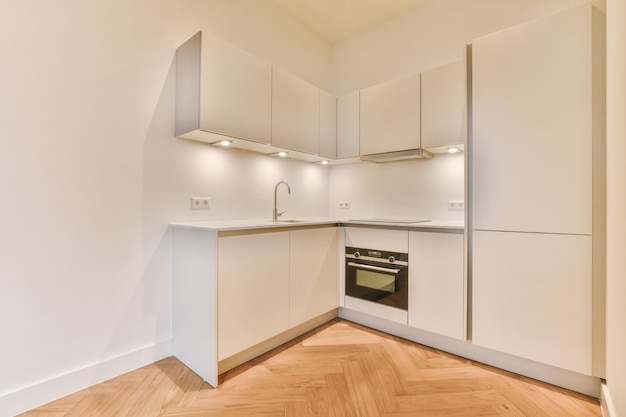 A spacious room with parquet floors and a corner kitchen in a minimalist style in a modern house