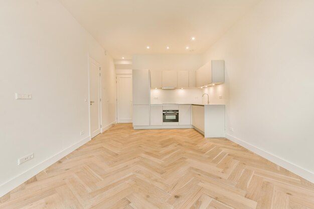 A spacious room with parquet floors and a corner kitchen