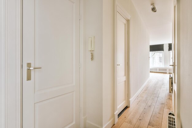 A spacious straight corridor with several doors on the sides leading inside to a cozy house