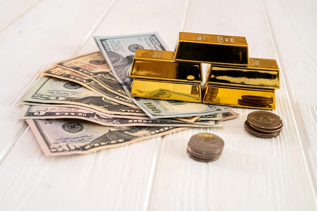 Su un tavolo spazioso sono presenti banconote da un dollaro con monete su cui sono presenti lingotti d'oro concetto di business