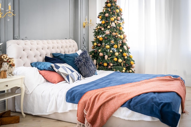 A spacious white light bedroom in a loft style with a decorated Christmas tree and a garland.