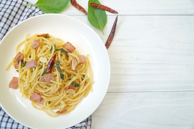 Spaghetti Aglio E Olio op witte plaat. Ham, knoflook, gedroogde chili, basilicum.
