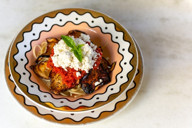 Spaghetti alla norma Italiaanse deegwaren met aubergines en tomaat en kaas op een plaat.