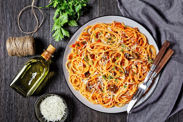 Spaghetti alla norma, klassieke pastaschotel van gebakken aubergine gegooid met tomatensaus en gegarneerd met geraspte Parmezaanse kaas geserveerd op een bord, Italiaanse keuken, horizontale weergave van bovenaf, plat leggen