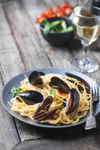 Spaghetti allo scoglio, pasta met zeevruchten, mosselen op een grijze keramische plaat over houten