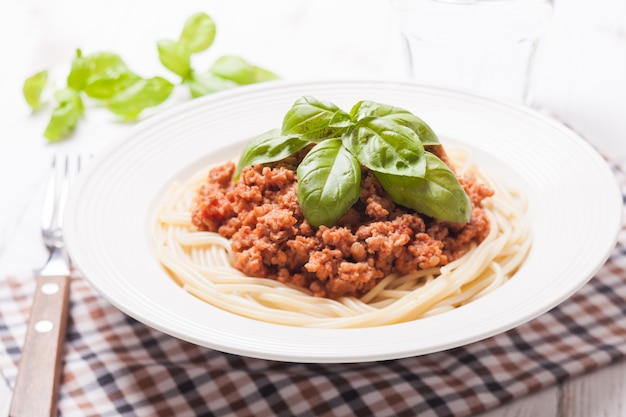 Спагетти болоньезе на тарелке и базилик