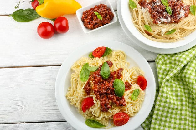 Spaghetti Bolognese on white plate on color wooden background