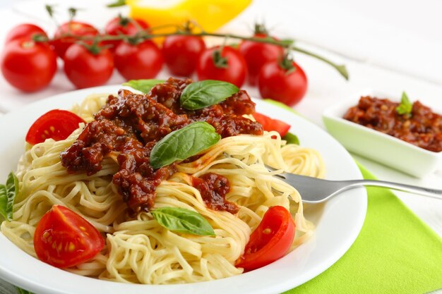 Spaghetti Bolognese on white plate on color wooden background