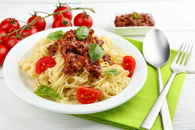 Spaghetti Bolognese on white plate on color wooden background