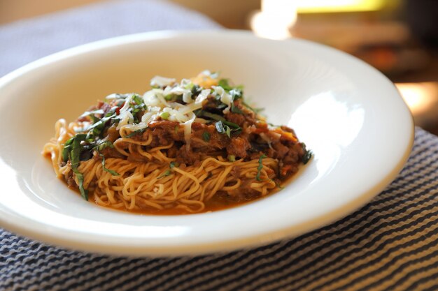 Spaghetti Bolognese with minced beef and tomato sauce garnished with parmesan cheese and basil , Italian food