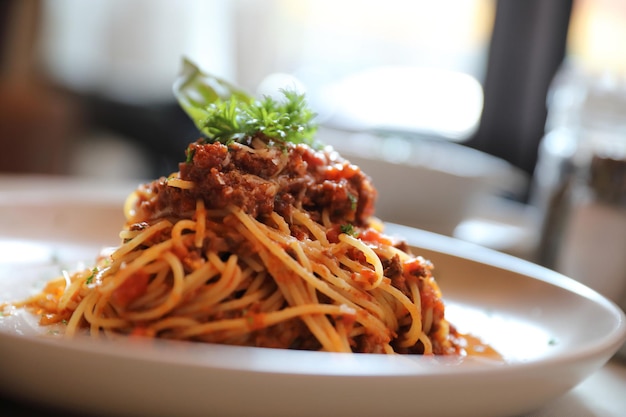 Spaghetti alla bolognese con carne macinata e salsa di pomodoro guarniti con parmigiano e basilico, cibo italiano